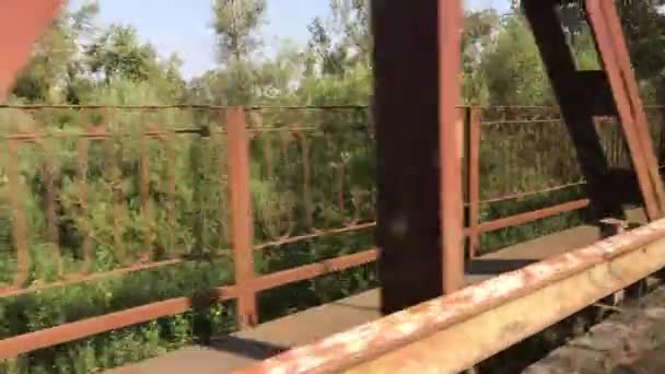 Disparos desde un coche en movimiento cuando se mueve a través de un puente sobre un río. Soportes de puente de metal parpadeado . — Vídeos de Stock