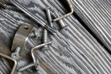 Vidalar için delikli metal köşeler. Tornavida ve vidaların yanında. Siyaha boyanmış çam tarama tahtalarının üzerinde yatıyorlar. Dünya İşçi Bayramı.