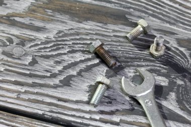 Bir avuç eski metal cıvata ve İngiliz anahtarı. Siyaha boyanmış çam tarama tahtalarının üzerinde yatıyorlar. Dünya İşçi Bayramı.