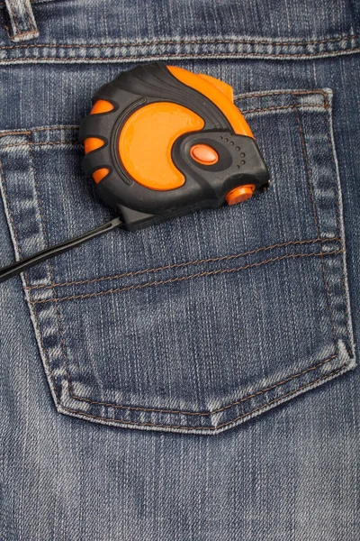 Arka cebinde turuncu ve siyah elementlerin asılı olduğu bir mezura var. İşçi Bayramı 'nın sembolü.