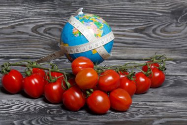 Ölçüm bandıyla sarılmış küre. Bir sürü domatesin yanında. Çam ağacından yapılmış tahtalarda. Diyet Günü Olmayan Dünya Sembolü.