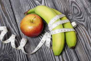 Muz, mezura ve elma. Çam ağacından yapılmış tahtalarda. Diyet Günü Olmayan Dünya Sembolü.