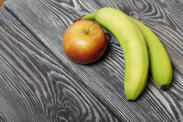 Bananas and an apple. On brushed pine boards. Symbol of World No Diet Day.