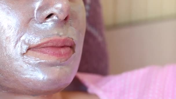 Een vrouw verwijdert een zilveren cosmetische folie masker met colloïdaal zilver van haar gezicht. Zorg voor een probleemhuid. Vrouw gezicht geschoten close-up. — Stockvideo