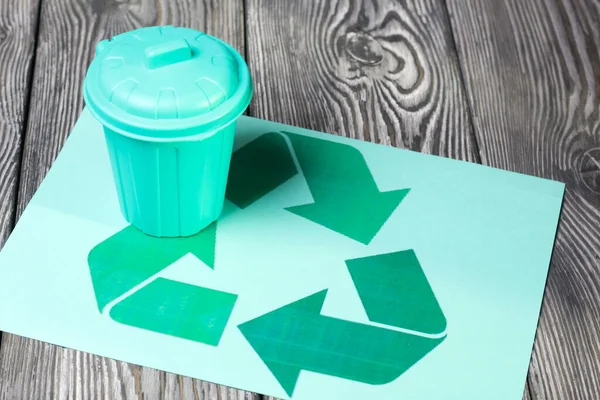 Trash can with a lid stands on the waste recycling symbol. Symbol of environmental protection day.