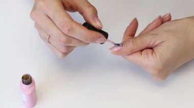 Kız nazikçe tırnaklarına jöle sürüyor. Manikür yapıyor. Bir kavanoz verniğin yanında. Evde kendine iyi bak. Yakın çekim..