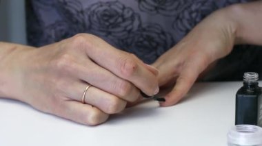 Kız manikür yapıyor. Jel cilası sürüyor. Yakın çekim..