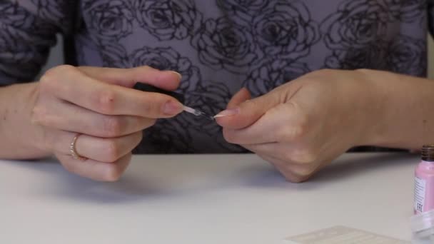 La fille avec un masque de protection fait de la manucure. Appliquez du vernis gel sur les ongles. Près des outils pour la manucure. Gros plan — Video