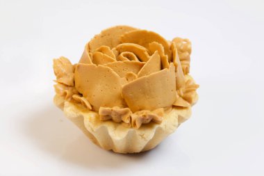 Krem şantili çiçeklerle süslenmiş yarım bir pasta. Kremanın karamel rengi var. Fırçalanmış çam ağaçlarında siyaha boyanmış.