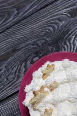 Kremayla süslenmiş pasta. Dekorasyonun üstüne kar taneleri şeklinde. Fırçalanmış çam ağacından yapılmış tahtaların üzerinde..