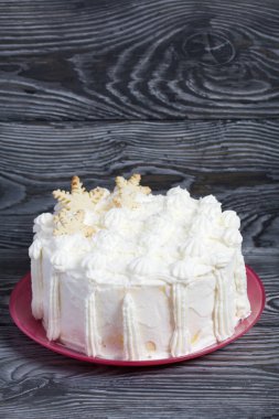 Kremayla süslenmiş pasta. Dekorasyonun üstüne kar taneleri şeklinde. Fırçalanmış çam ağacından yapılmış tahtaların üzerinde..