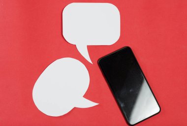 Akıllı telefon blogcusu. Konuşma baloncuklarının yanında. Mercan renginin arka planına karşı.