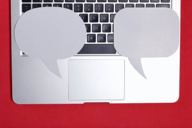 Blogger 'ın bilgisayarı. Klavyede farklı boyutlarda ve şekillerde konuşma baloncukları var. Mercan renginin arka planına karşı.