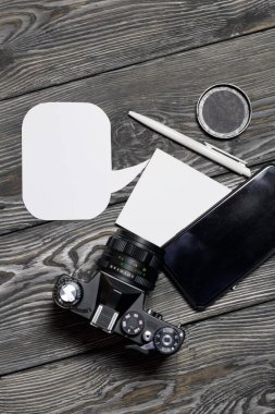 Akıllı telefon ve kamera blogcusu. Defter ve kalemin yanında. Konuşma baloncukları. Fırçalanmış çam ağaçlarının arka planında.