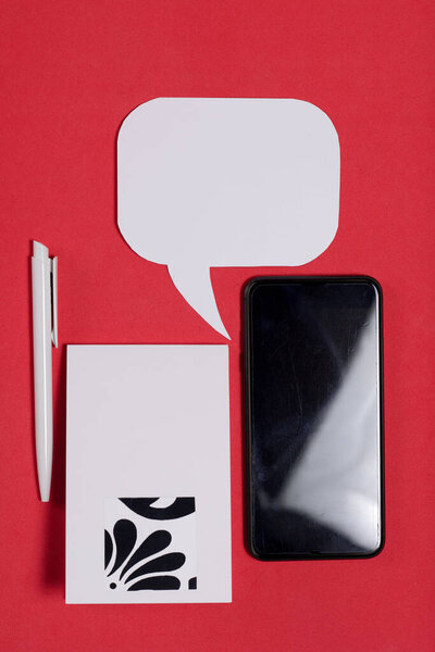 Smartphone blogger. Near a notebook and pen. Around speech bubbles. Against the background of coral color.
