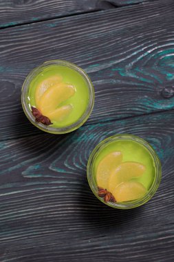 Beyaz ve yeşil kremalı jöle. Şeftali dilimleri ve anason yıldızıyla süslenmiş. Yukarıdan ateş edildi.