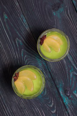 Beyaz ve yeşil kremalı jöle. Şeftali dilimleri ve anason yıldızıyla süslenmiş. Yukarıdan ateş edildi.