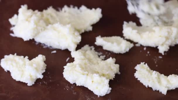 Frau legt Kokosmasse auf einen gerollten braunen Teigklumpen. Zutaten für die Zubereitung von Dessert. — Stockvideo