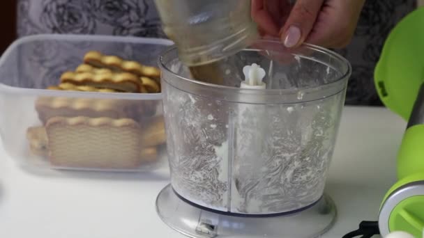 Gadis menempatkan kakao dalam mangkuk blender. Itu mematahkan kue dan melemparkannya di sana juga. Untuk membuat makanan penutup. — Stok Video