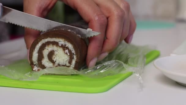 Eine Frau schneidet eine Rolle, die mit Kokosnüssen gefüllt ist. Nachtisch kochen. — Stockvideo