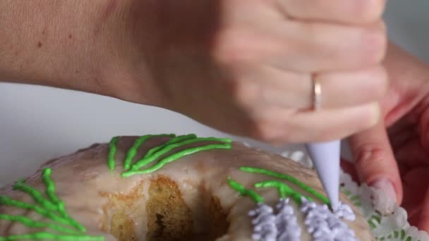 Pastelito de azúcar. Mujer pinta flores de lavanda con esmalte. Usando una bolsa de pastelería . — Vídeos de Stock