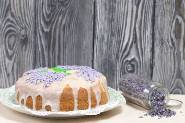 Lavantalı kek. Şeker kaplı. Lavanta rengi çiçeklerle süslenmiş. Lavanta kabartılarıyla bankanın yanında..