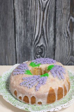 Lavantalı kek. Şeker kaplı. Lavanta rengi çiçeklerle süslenmiş. Küçük bir parça kesilmiş..