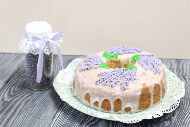 Lavantalı kek. Şeker kaplı. Lavanta rengi çiçeklerle süslenmiş. Lavanta kabartılarıyla bankanın yanında..