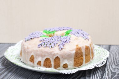 Lavantalı kek. Şeker kaplı. Lavanta rengi çiçeklerle süslenmiş. Küçük bir parça kesilmiş..