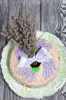 Lavantalı kek. Şeker kaplı. Lavanta rengi çiçeklerle süslenmiş. Bir demet lavantanın yanında..