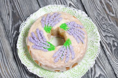 Lavantalı kek. Şeker kaplı. Lavanta rengi çiçeklerle süslenmiş. Küçük bir parça kesilmiş..