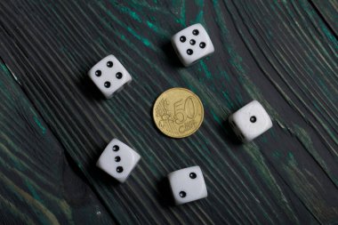 Siyah noktalı beyaz zarlar ve bozuk para. Çam ağacından yapılmış tahtalarda.