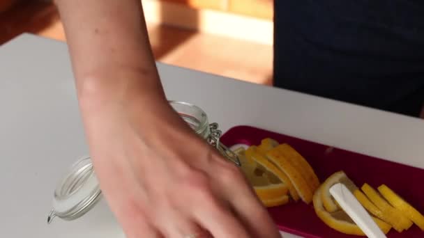 La donna mette rosmarino, fette di limone, pepe e sale in un barattolo di vetro. Miscele limone salatura ingredienti . — Video Stock