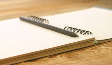 tahta bir masanın üzerinde yatan yer imleri ile üstünde defter kalem