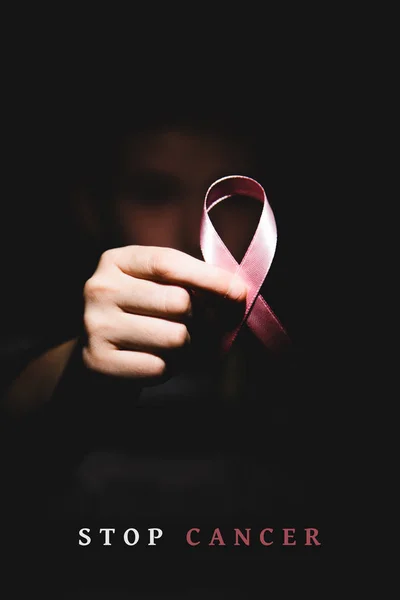 Red aids ribbon in hand on black background, Color in black and — Stock Photo, Image