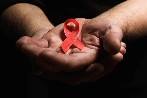 Yaşlı bir adam kırmızı AIDS şerit tutan eller. Tex bir sürü