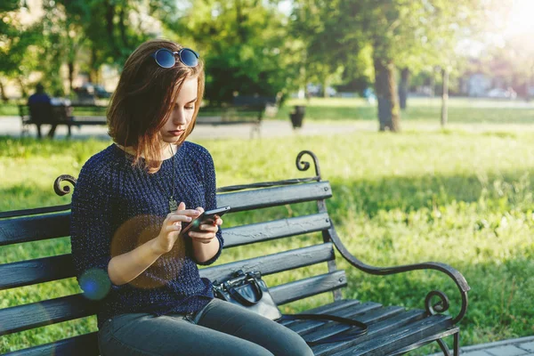 Güzel mutlu kız karşılık gelen bir parkta sosyal ağlar üzerinde 