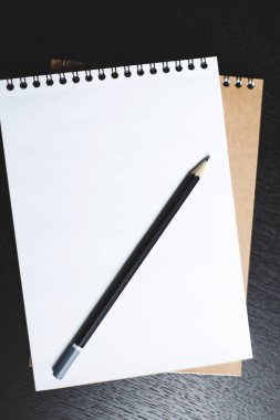 Koyu ahşap bir masa üzerinde bir siyah kalem ile defter