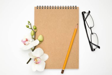 Beyaz bir masanın üzerinde yatan gözlük ve kalem, office kavramı ile defter