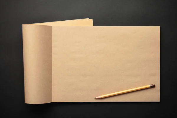 Kraft notitieboekje met potlood op zwarte achtergrond, ambachtelijke Opmerking pad — Stockfoto