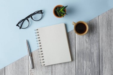 Defter, kalem, bardak, fincan kahve ve yeşil çiçek ile açın