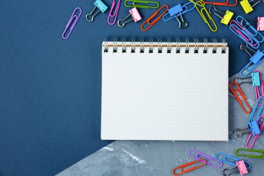 Defter ve siyah ve gri arka plan üzerinde renkli ataç