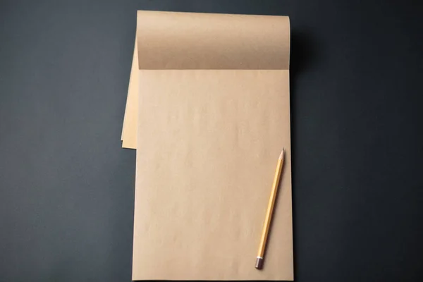 Cuaderno Kraft con lápiz sobre fondo negro, bloc de notas artesanal —  Fotos de Stock
