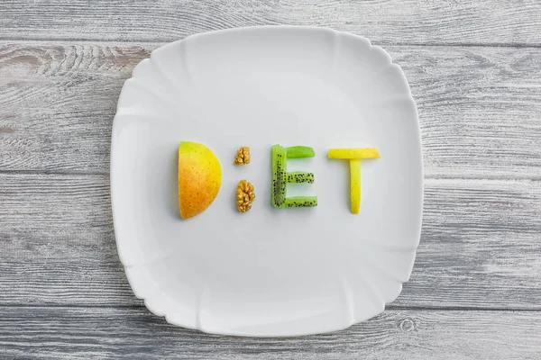 Obst auf einem Teller mit einem Wort Diät von Apfel, Kiwi, Karotten, Nüssen und — Stockfoto