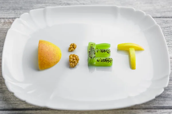 Obst auf einem Teller mit einem Wort Diät von Apfel, Kiwi, Karotten, Nüssen und — Stockfoto