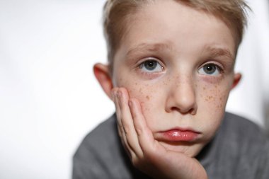 Arka planda çok üzgün küçük bir çocuk.