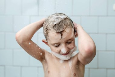 Küçük çocuk duşta yıkanıyor.