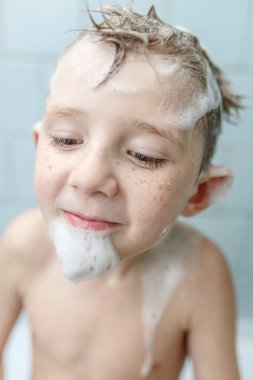 Küçük çocuk duşta yıkanıyor.