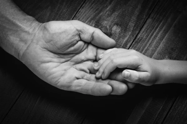 Ruce staršího muže, který drží ruku mladšího muže. Černobílá. — Stock fotografie