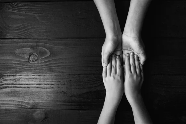 Brazos se extiende y se sostiene unos a otros sobre un fondo de madera negra.blanco y negro . —  Fotos de Stock